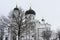 White Orthodox Church with a black dome on the background of branches with frost