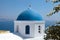 White orthodox church with blue dome, Santorini island, Greece.