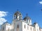 White Orthodox church and gray dome roof with metal crosses on the top against blue sky.