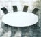 White oval conference table with black leather chairs on concrete floor