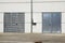 White Overhead Steel Garage Door On Exterior Of Beige Metal Building With Red Bumper Posts