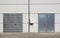 White Overhead Steel Garage Door On Exterior Of Beige Metal Building With Red Bumper Posts