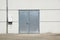 White Overhead Steel Garage Door On Exterior Of Beige Metal Building With Red Bumper Posts