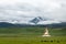 The white pagoda of Tibetan Buddhism on the grassland at the foot of the snow-capped mountains