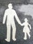 White paint of adult and child walking hand in hand on black asphalt surface of a footpath.