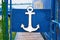 White painted anchor sign on blue door.