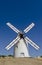 White painted windmill with sails against a blue sky