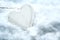 White painted wooden heart shape lying in the snow  seasonal winter love symbol for valentines day  new year or chrismas  copy