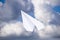 White paper airplane in a blue sky with clouds. The message symbol in the messenger