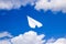 White paper airplane in a blue sky with clouds. The message symbol in the messenger