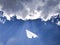 White paper airplane in a blue sky with clouds. The message symbol in the messenger