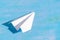 White paper airplane lies on a wooden blue background. View from above.