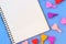 White paper and colored hearts on a blue background. Concept notes for Valentine`s Day