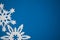 White paper handmade snowflakes on blue colored paper background