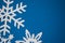 White paper handmade snowflakes on blue colored paper background