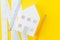 White paper house, yellow pencil and white measuring tapes with centimetre and inches on vivid yellow background, architecture,