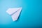 White paper origami airplane lies on pastel blue background