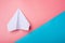 White paper origami airplane lies on pastel colors background