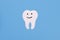 White paper smiling tooth on a blue background. Dental treatment, dentist services, oral care