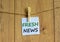 White paper with words `fresh news`, clip on wood clothespin. Beautiful wooden background. Business and fresh news concept. Copy