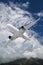 white passenger plane flies against the mountains with white clouds on blue sky background.  Landscape with airplane, mountains