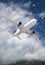 white passenger plane hurtles through rushing snow against a backdrop of mountains with white clouds.  Landscape with airplane,