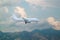 white passenger plane landing against the mountains with white clouds on blue sky background.  Landscape with airplane, mountains