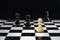 A white pawn stands on a chessboard against black pawns. Victory concept