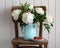 White peonies in an enameled jug and red strawberries on an old chair. Cottage core