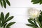 White peony flower and leaves on white rustic wooden background with blank space for text. Mockup, top view