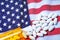 White pharmaceutical pills spilling from prescription bottle over American flag