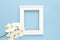 White photo frame with white orchids. Beautiful White Phalaenopsis orchid flowers, wooden white photo frame on blue background