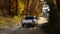 White pickup truck driving down dusty dirt road with fall leaves and dust behind