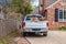 White pickup truck full of trash-boards and boxes- parked in driveway of brick house by security fence - ready to haul it away