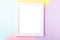 White picture frame on pastel pink, yellow, blue multicolor geometric background. Mockup on colorful table top, copy