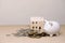 white piggy bank Coins and houses on a wooden table, for saving money wealth, and financial concepts, save home loan.