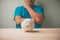 A white piggy bank on a wooden table with a man consider a white piggy bank to plan to save money for Investment future use.