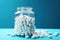 White pills in a glass jar on blue background. Focus on foreground.