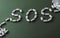 White pills on green background, which forming the word - SOS, with a blister of pills on background.