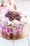 White and pink birhday cake with meringues and fresh berries, raspberries, strawberries and blueberries