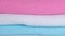 White, pink and blue clean towels and a cotton branch on a white background. Closeup Slow motion