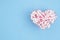 White and pink cotton swabs in a heart container on blue paper background