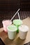 White, pink and green milkshakes in transparent cups with a straw. vertical view