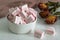 White-pink marshmallow on a light table next to a bouquet of wild field dried flowers. Sweets for tea and coffee on a porcelain