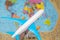 White plane with blue wings on the background of the atlas of the world. The concept of travel around the world