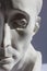 White plaster statue of half mans head on blue grey background