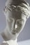 White plaster statue of woman head on blue grey background, close up