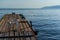 White plastic chair sits on wooden dock by the blue calm sea, pier on shore, coast of Lake Baikal. Clear horizon with mountain