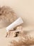 White plastic cream tube on stone near dry pampas grass on light beige, Mockup