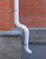 White plastic curved downpipe on red brick wall